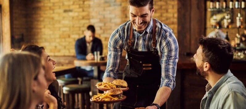 waiter serving diners at restaurant