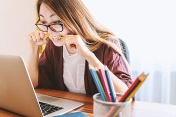 woman stressed by laptop biting a pencil